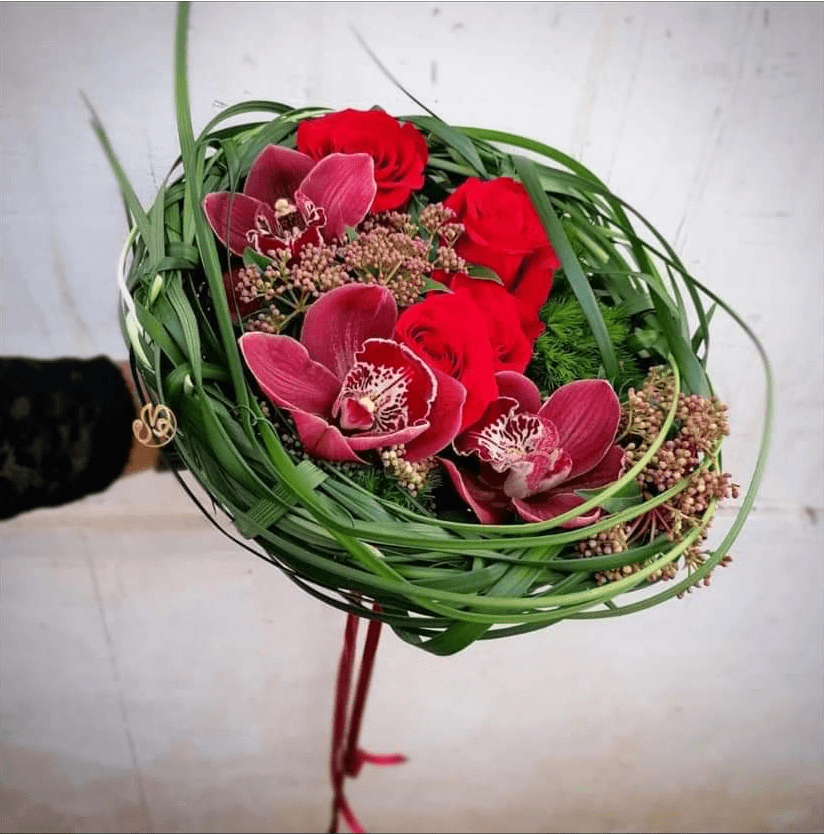Bouquet circolare con orchidee e rose rosse per ragazza laureata